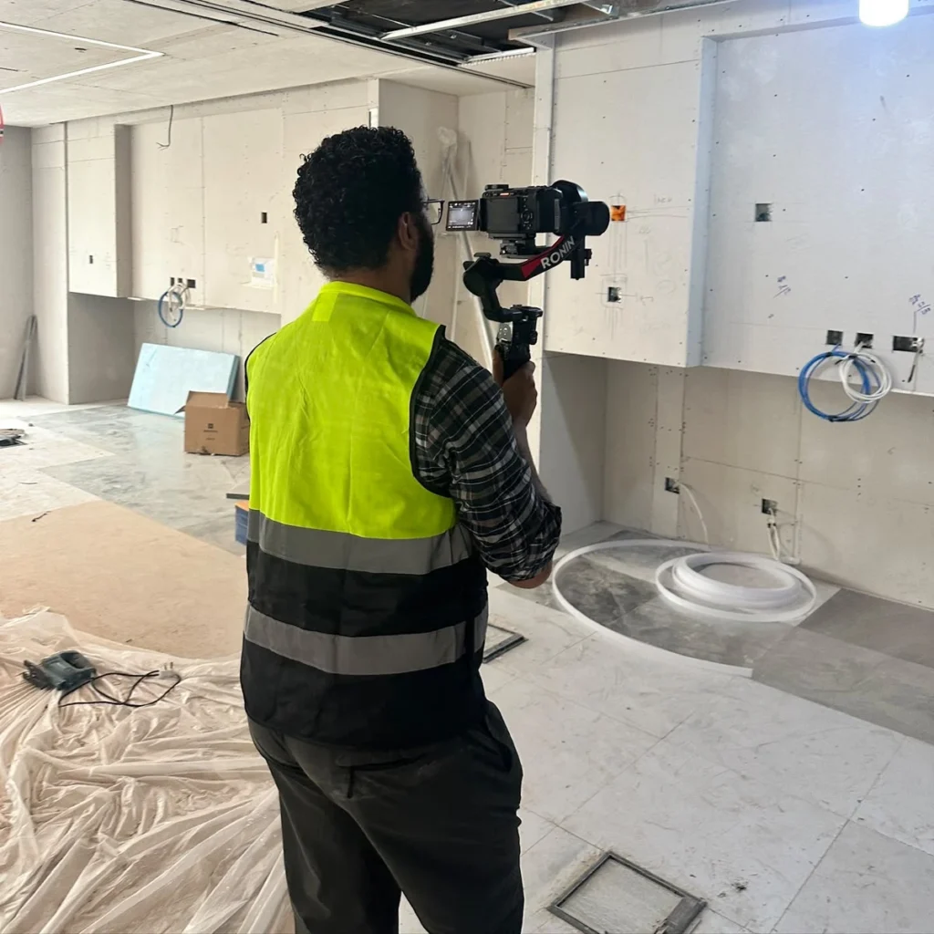 A videographer in a high-visibility safety vest tracking the progress during an office fit out filming session inside the KAFD facility.