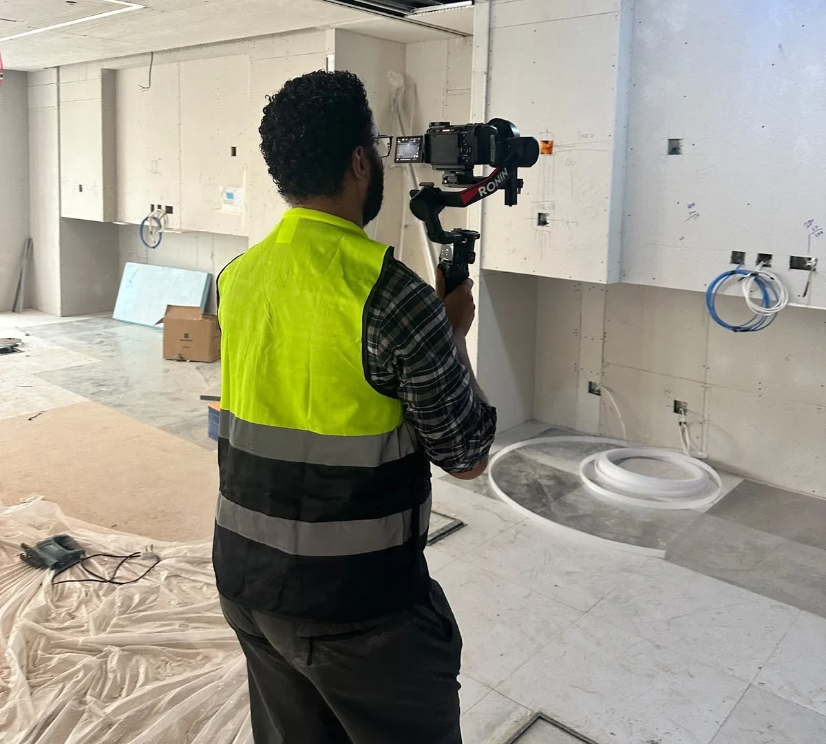 A videographer in a high-visibility safety vest tracking the progress during an office fit out filming session inside the KAFD facility.