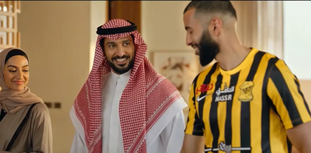 Saudi man in traditional attire standing beside a football player in a black and yellow jersey