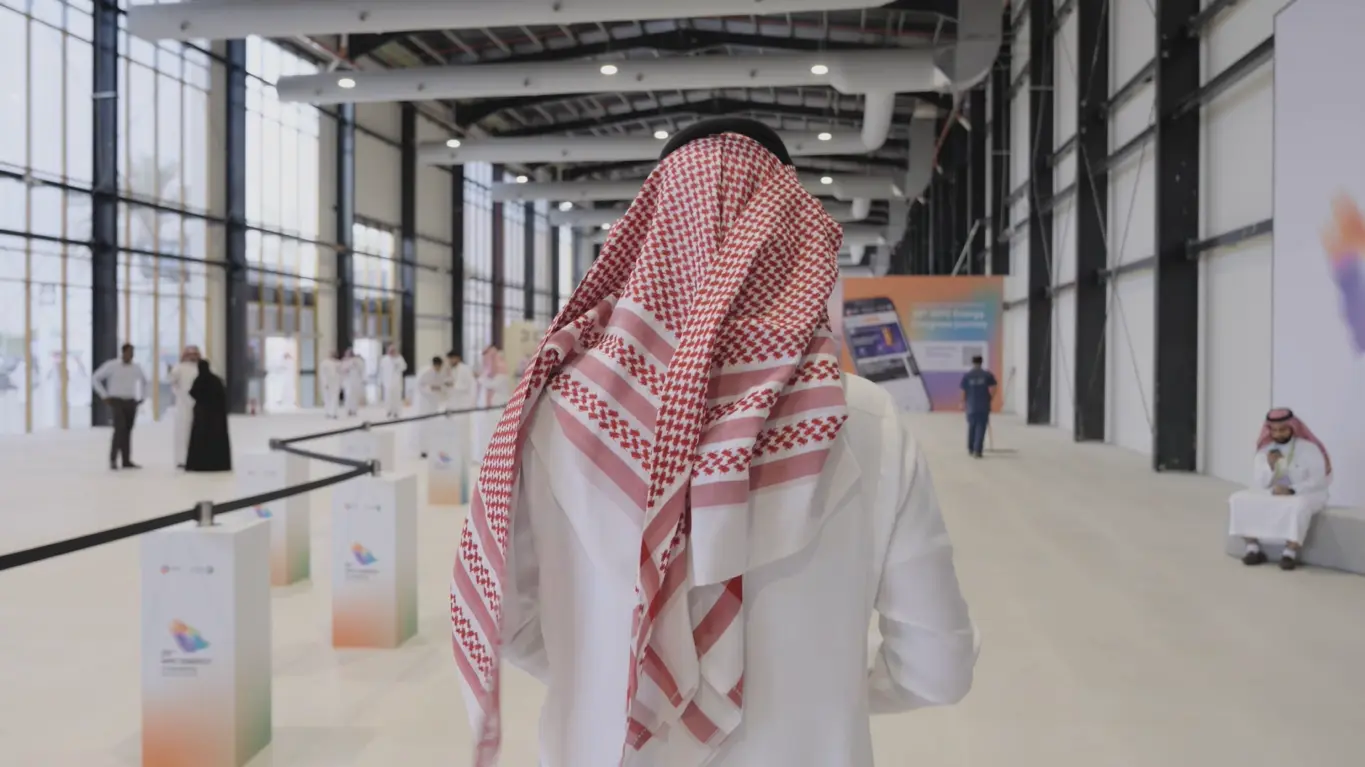 Attendee wearing traditional Saudi attire walking through the exhibition hall at the 25th WPC Energy Congress in Riyadh.