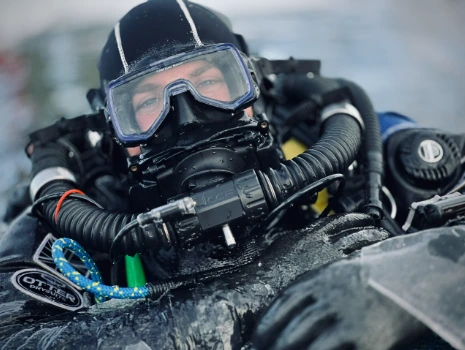 Underwater cinematographer operating a professional camera in waterproof housing while filming marine life and coral reefs.