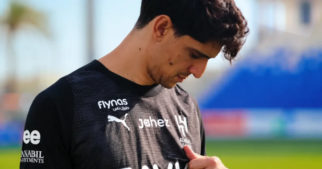 Al Hilal football player wearing a black training jersey, looking down while holding the club crest during a training session.